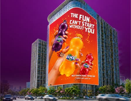 Fanta creative running on BIG ONE's curved display above a city street at dusk
